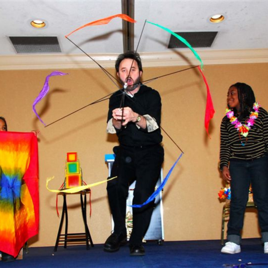 A magician twirls streamers during a trick.