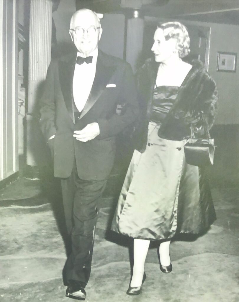 President Truman and Mrs. Truman walk through a lounge at the theatre.