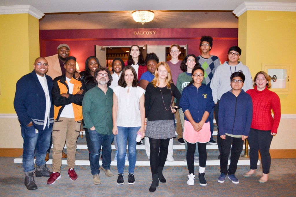 Tina Fey, Jeff Richmond, and Nell Benjamin pose for a picture with fourteen students at the theater.