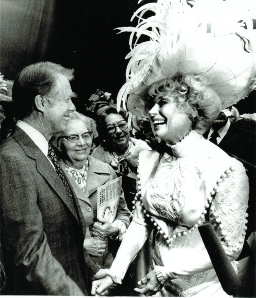 President Jimmy Carter meetings actress with large feathered hat. 