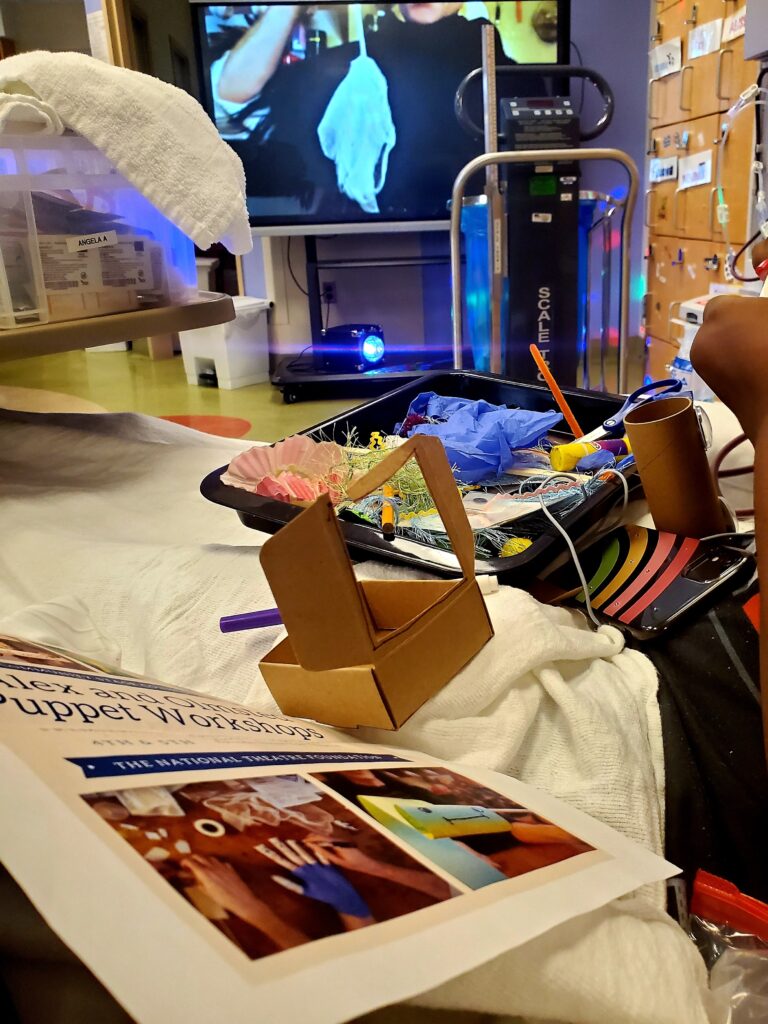 Photo of a patient at a hospital making a puppet out of cardboard and gloves.
