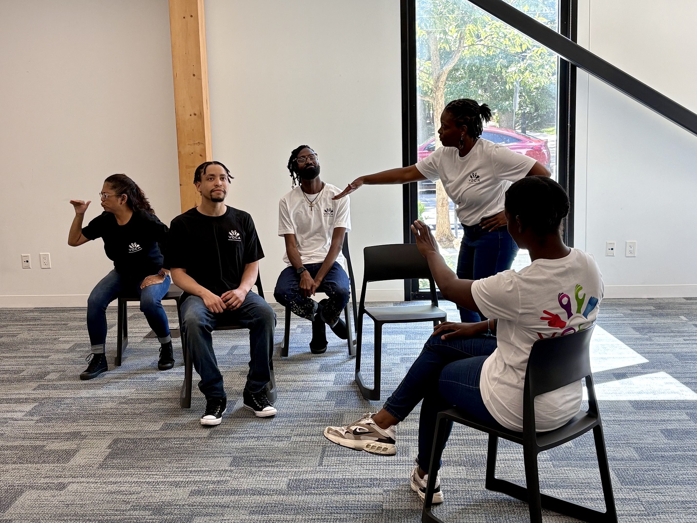An ensemble in black and white t-shirts poses during a performance in a room at Southwest Library.